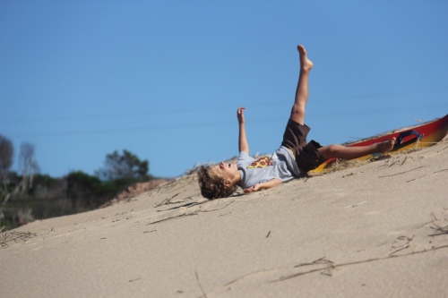 A young boy sand boarding in Punta del Diablo